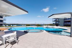 a large swimming pool in a building with a patio at BreakFree Grand Pacific in Caloundra