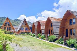 una hilera de casas de madera con árboles en Griya Cabin 2 Dieng Syariah RedPartner, en Diyeng