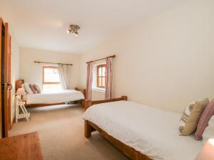 Un dormitorio con dos camas y una ventana. en Old Hall Barn 1, en Church Stretton