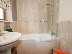 Un baño con bañera blanca y lavabo. en Old Hall Barn 1, en Church Stretton 18 fotos más