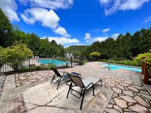 Studio Woodland by Gestion ELITE في مونت تريمبلانت: كرسيين وطاولة بجانب مسبح