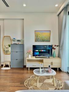 Una sala de estar con televisión y una mesa de café. en Vinhomes Smart City Luxury Apartment, en Phú Thú