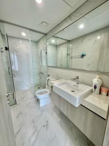 Un baño blanco con lavabo e inodoro. en Vinhomes Smart City Luxury Apartment, en Phú Thú