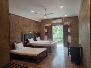a bedroom with two beds and a desk in it at Hotel Riverrina in Negombo