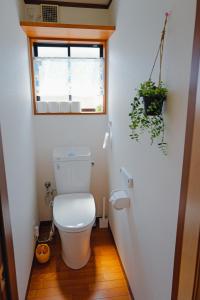 a bathroom with a toilet with a window and a plant at Akira Hiro House - Room101 in Tokyo +11 photos