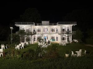 a large white house with white lawn chairs at night at Moustache Hostel Bir in Bīr