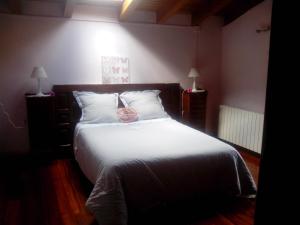 a bedroom with a white bed with a pink bag on it at Dukebaso in Durango