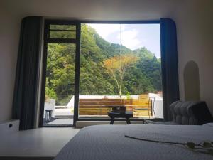 a bedroom with a large glass door to a balcony at Zhangjiajie MUYE HOTEL in Jiawan