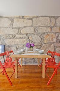 una mesa de madera con 2 sillas rojas y una pared de piedra en Porto Sé Apartamentos en Oporto