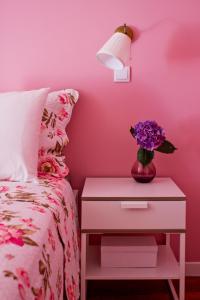 a pink bedroom with a bed and a table with a vase of flowers at Porto Sé Apartamentos in Porto