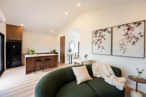 a living room with a green couch and a kitchen at Moritz Hahndorf Boutique Guest House in Hahndorf