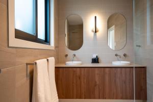 a bathroom with two sinks and two mirrors at Moritz Hahndorf Boutique Guest House in Hahndorf +7 photos