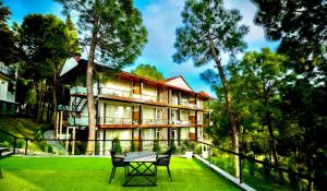 a house with a table and chairs in front of it at adiMOUNT-Kumaon Eco Resort in Dwārāhāt