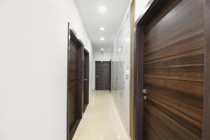 Un pasillo con puertas de madera y un pasillo con azulejos blancos. en FabHotel Classic Comfort, en Amritsar