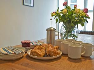 a table with a plate of pastries and a vase with flowers at Bristol House in New Quay
