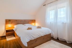 Un dormitorio con una gran cama blanca con ventana. en Plitvice Lakes Apartments & Rooms, en Grabovac