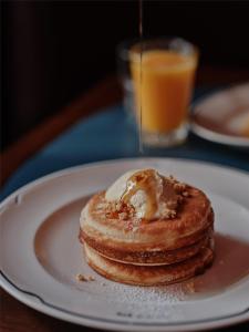 een stapel pannenkoeken op een wit bord met stroop bij The EVE Hotel Sydney in Sydney