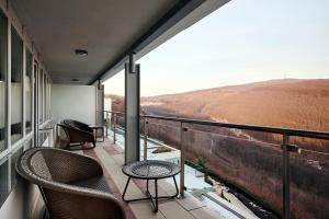 a balcony with chairs and a view of a field at Hotel Ózon & Luxury Villas in Mátraháza