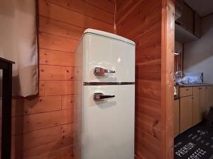 a white refrigerator in a kitchen with wooden walls at アルミテラーノ矢板 in Yaita
