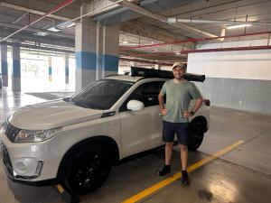 a man standing next to a white truck in a garage at Zeus Guesthouse -Free SJO Airport Shuttle & Car Rental in La Garita