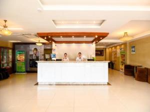 two people standing at a counter in a lobby at GreenTree Inn Hotel - Nantong Hongming Plaza in Nantong