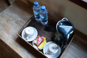 a tray with two bottles of water and plates and drinks at Pondok Sadia Villa in Tegalalang