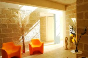 a room with orange chairs and a brick wall at Cave Bianche Hotel in Favignana
