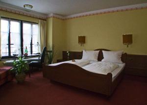 ein Schlafzimmer mit einem großen Bett mit weißer Bettwäsche und Kissen in der Unterkunft Hotel Beller in Kenzingen