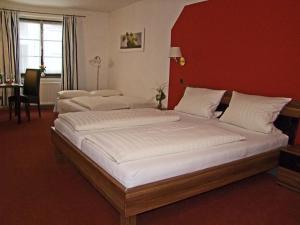 2 Betten in einem Schlafzimmer mit einer roten Wand in der Unterkunft Hotel Beller in Kenzingen