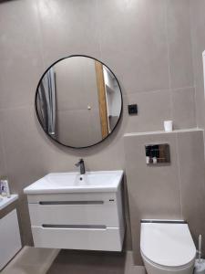 une salle de bains avec un lavabo blanc et un miroir dans l'établissement 24 home Aktau, à Aktau