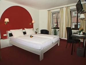ケンツィンゲンにあるHotel Bellerのベッドルーム1室(赤いヘッドボード付きの大型ベッド1台付)