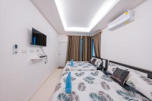 a bedroom with two beds and a tv on the wall at Flamingo Na Jomtien in Na Jomtien