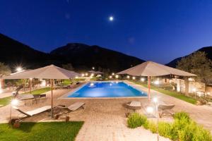 a pool with chairs and umbrellas at night at Antico Casale Urbani in Scheggino