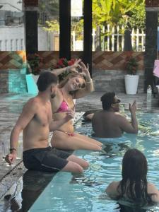 a group of people sitting in a swimming pool at Riverside Hoi An, Dolphins Hostel in Hoi An