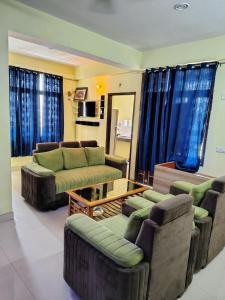 - un salon avec des canapés, une table et des rideaux bleus dans l'établissement Luxury Retreat 3 BHK Flat For Family and Group Homestay, Prime Location Near Kashi Vishwanath Temple, à Varanasi