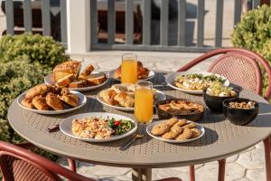 a table filled with plates of food and orange juice at Niléa Island Living in Agia Anna Naxos +74 photos