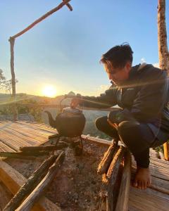 a man is cooking in a pot on a stove at Homestay Nunga หนูหง่าโฮมสเตย์กิกอคอ in Pang Mapha +2 photos