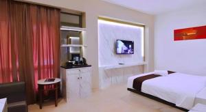 a hotel room with a bed and a tv in it at Grand Malioboro Yogyakarta in Yogyakarta