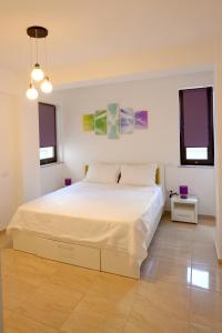 1 Schlafzimmer mit einem weißen Bett und 2 Fenstern in der Unterkunft Apartamente Seashells Mamaia Nord in Mamaia Nord – Năvodari