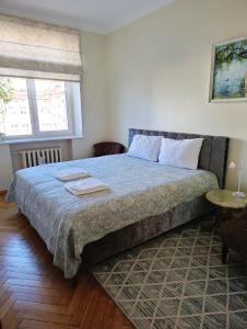 a bedroom with a bed with a blue blanket and two windows at Heart of Kaunas Apartament in Kaunas