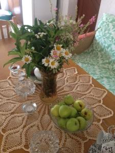 a table with a vase of flowers and a bowl of fruit at Eco Garten Guest House in Shkodër