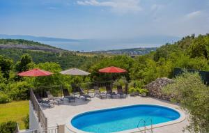 a swimming pool with chairs and umbrellas on a hill at Villa Stanzia Natura Crikvenica by Villas Guide in Bakarac