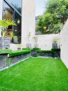 DargaiにあるSerene Stays-Your Home Away From Home In Islamabadの緑の芝生とベンチのある庭園