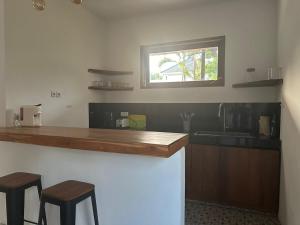 une cuisine avec un comptoir avec deux tabourets et un évier dans l'établissement Villa Vindo - 1BR & Swimming pool, à Kuta Lombok