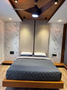a bedroom with a bed with a ceiling fan at Suvarna Millennium Suits in Mysore