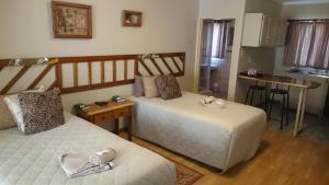 a bedroom with two beds and a kitchen in the background at Ladybrand Guest House in Ladybrand