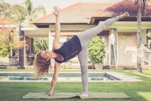 a woman doing a yoga pose in front of a house at Villa Fleur in Tumbak Bayuh