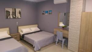 a bedroom with two beds and a desk and a chair at Aimilias Family Apartments in Nea Vrasna