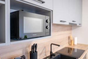 a microwave on a wall above a kitchen sink at Luxapartment ll Krivá in Košice +6 photos
