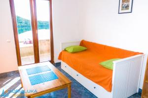1 dormitorio con cama de color naranja y mesa en Apartments Adrialuka, en Dubrava